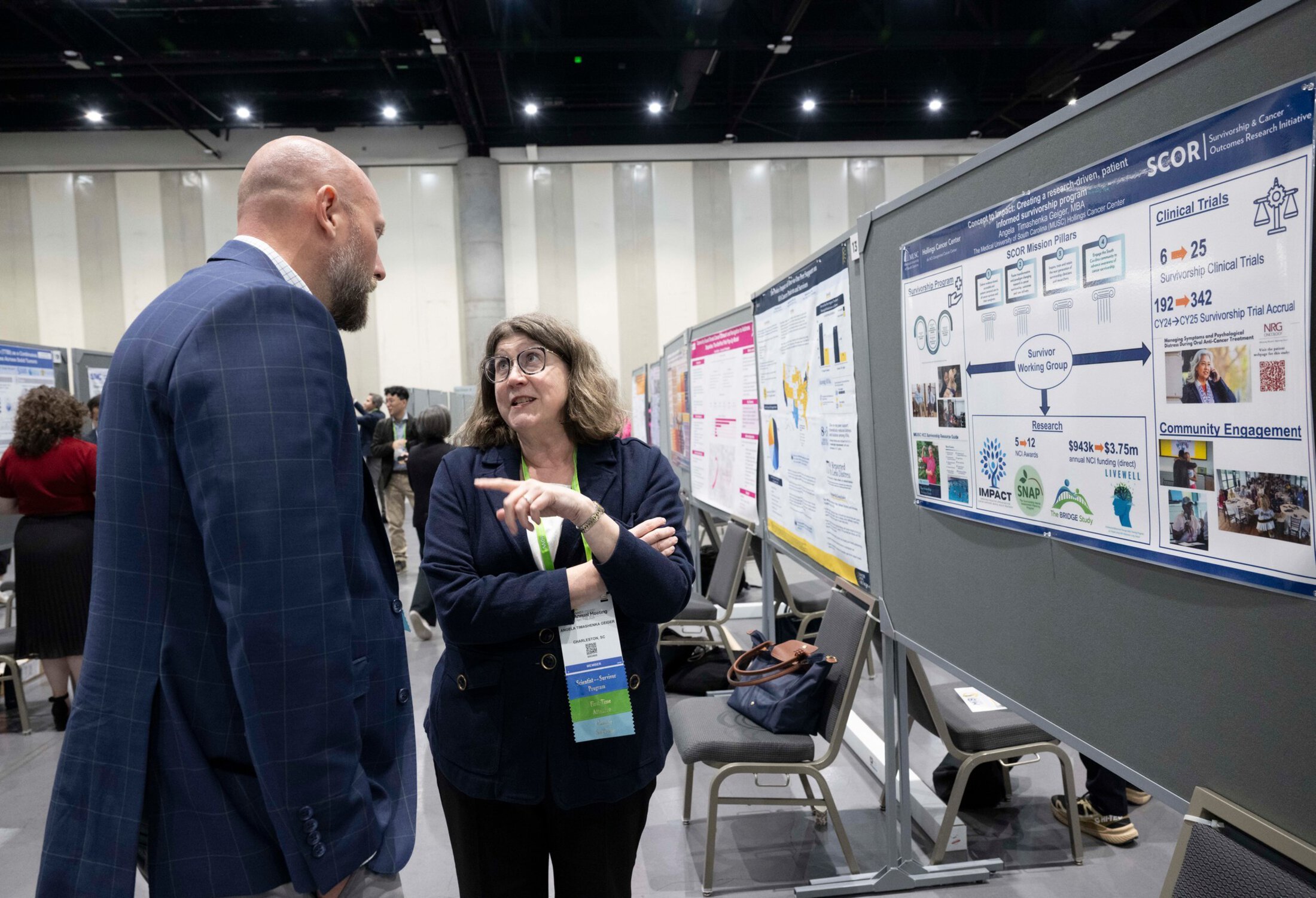 A woman chats with a man while standing in front of a poster at a scientific poster presentation.