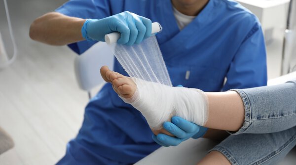 Doctor bandaging patient's foot in clinic, closeup