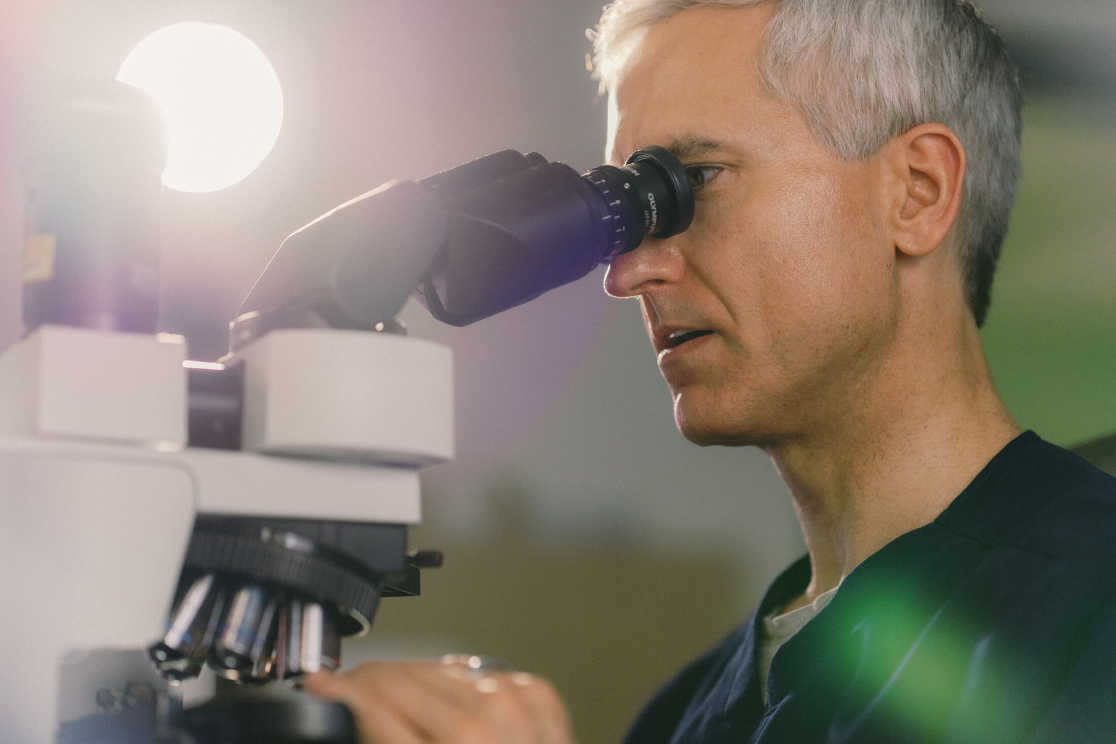 A man looks into a microscope.