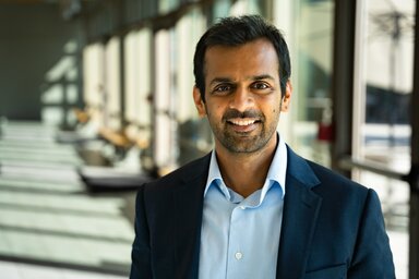 Ashish Deshmukh in a blue blazer and dress shirt in a sunlit hall.