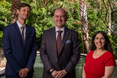 Three tobacco use researchers pose together in a garden setting.