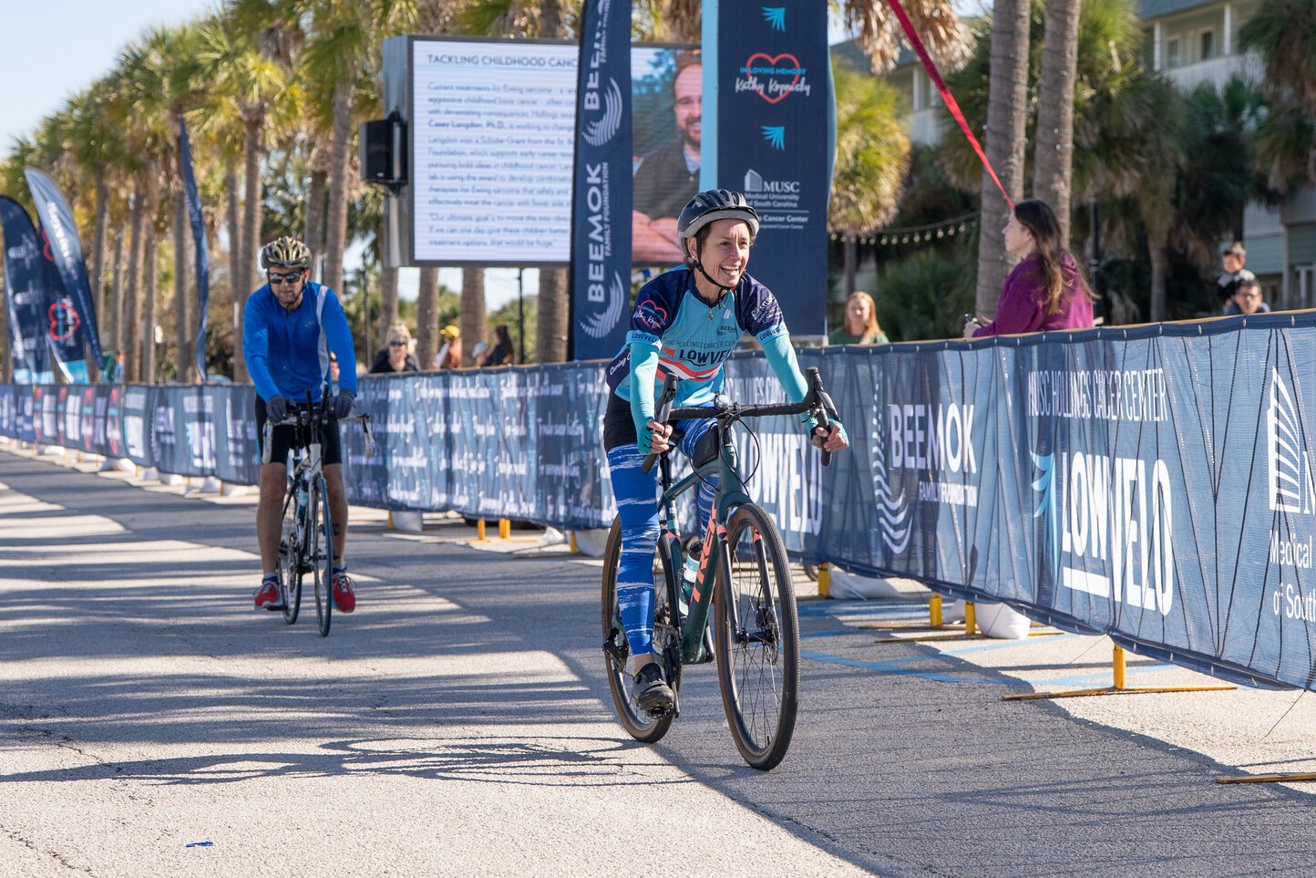 A woman smiles broadly as she crosses the finish line in a bike ride.