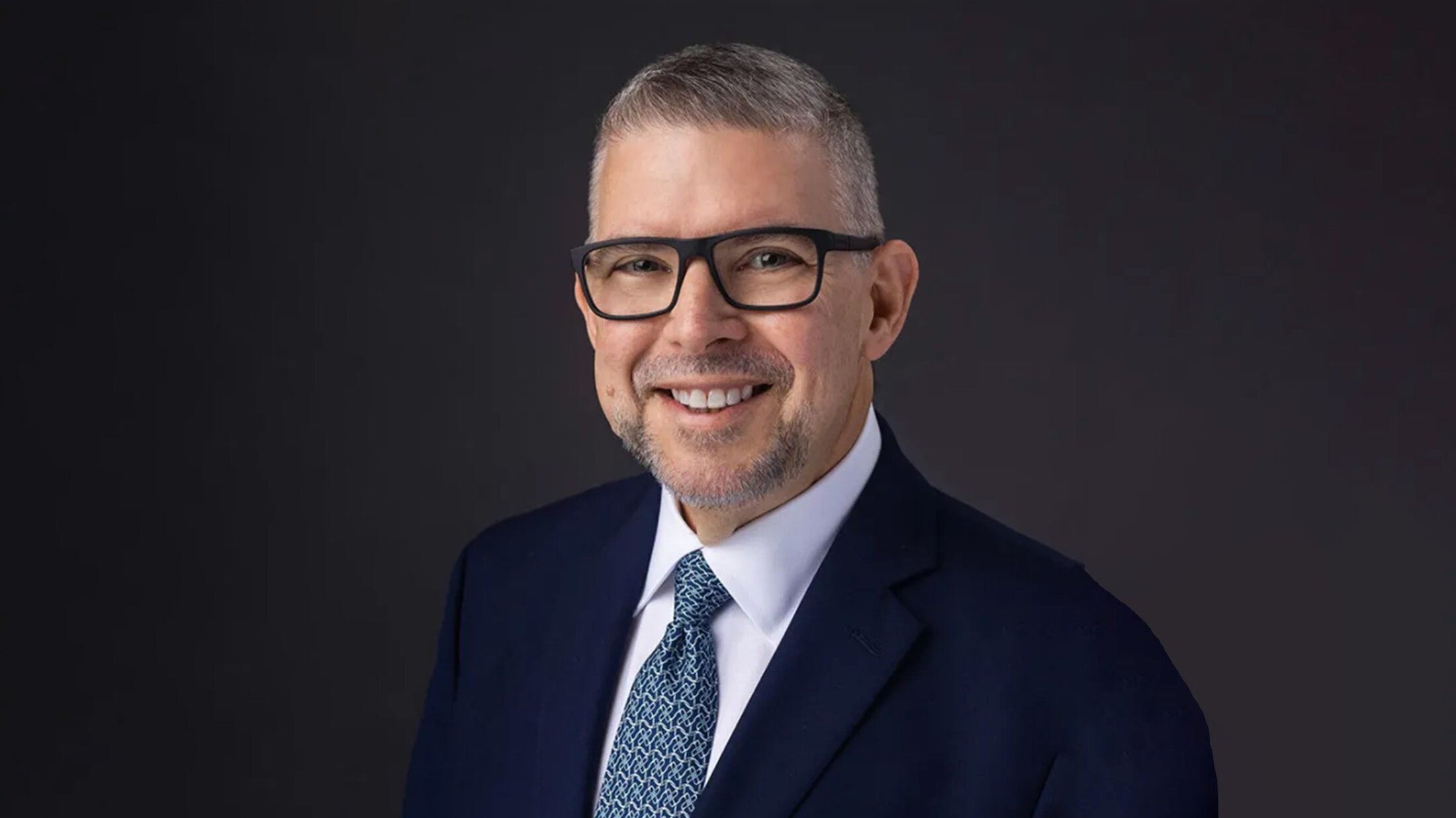 headshot of Frank Penedo in a navy blue suit and blue patterned tie