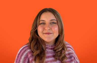 head and shoulders portrait of a young woman on a solid orange background