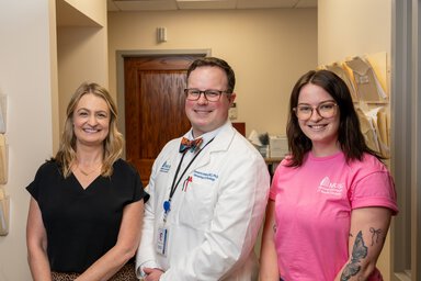 A doctor and two nurses in a clinic hallway.