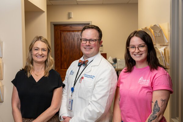 A doctor and two nurses in a clinic hallway.