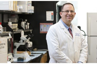 Doctor in white coat standing in lab.