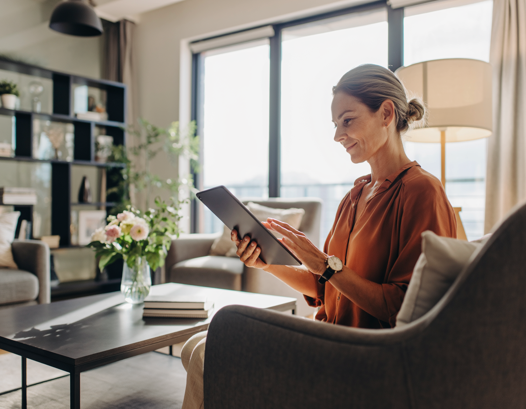 Woman sitting in a living room using a tablet during a telehealth appointment.