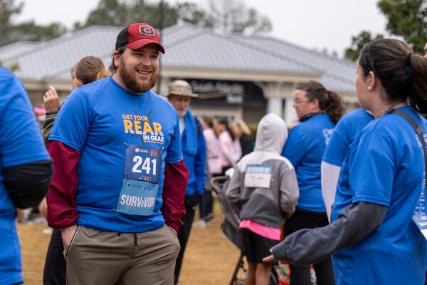 people in race t-shirts mingle after a community 5K fundraising event