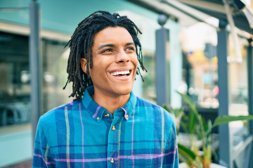 Young african american man smiling happy looking to the side at street of city.