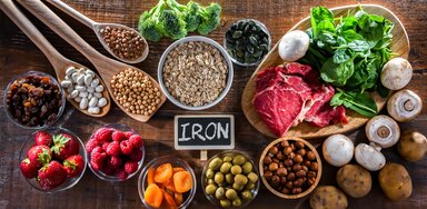 Beans, berries, apricots, olives, potatoes, mushrooms, steak, spinach and broccole surround a small chalkboard with the word 