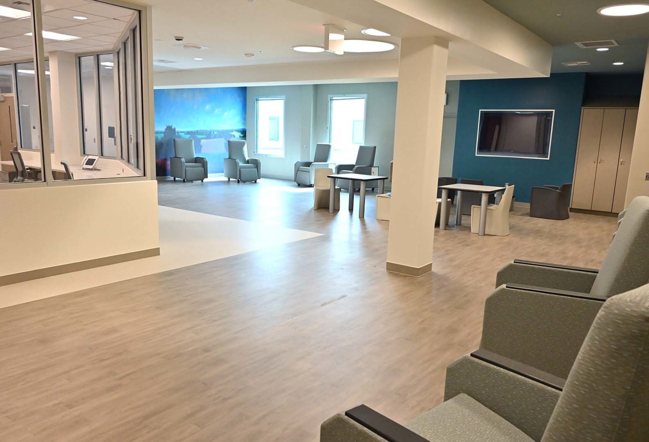 Chairs, tables and a reception desk. The colors are muted, browns and blues. There are two large windows.