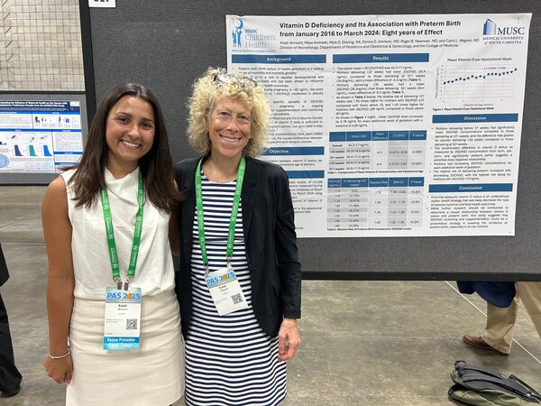 Two participants stand in front of a conference board highlighting vitamin d deficiency and preterm birth