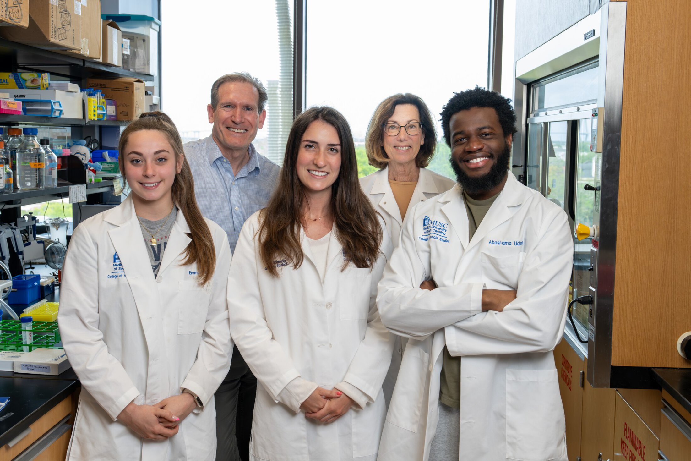 A group of senior and junior researchers pose together in a lab.
