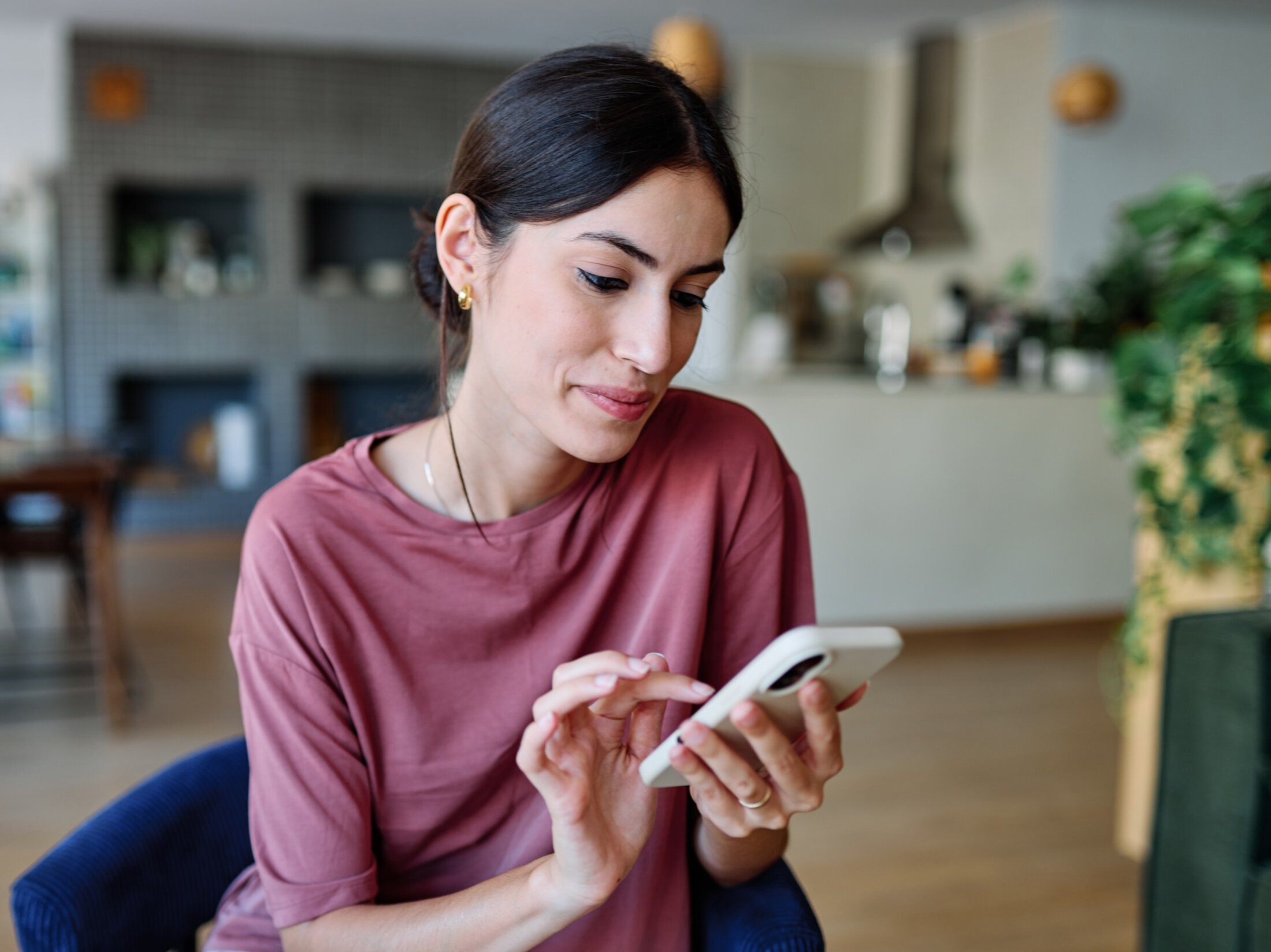 Portrait of a young latina woman chatting with boyfrien at home, using modern mobile phone, checking social media, using mobile app, texting or browsing internet on her phone, sitting on sofa at home