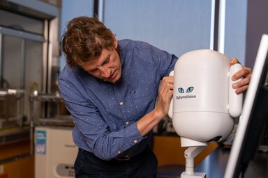 Dr. Haemmerich positions the SphynxVision device on a tabletop. It has a compact design, slightly longer than a football, with handles on either side.
