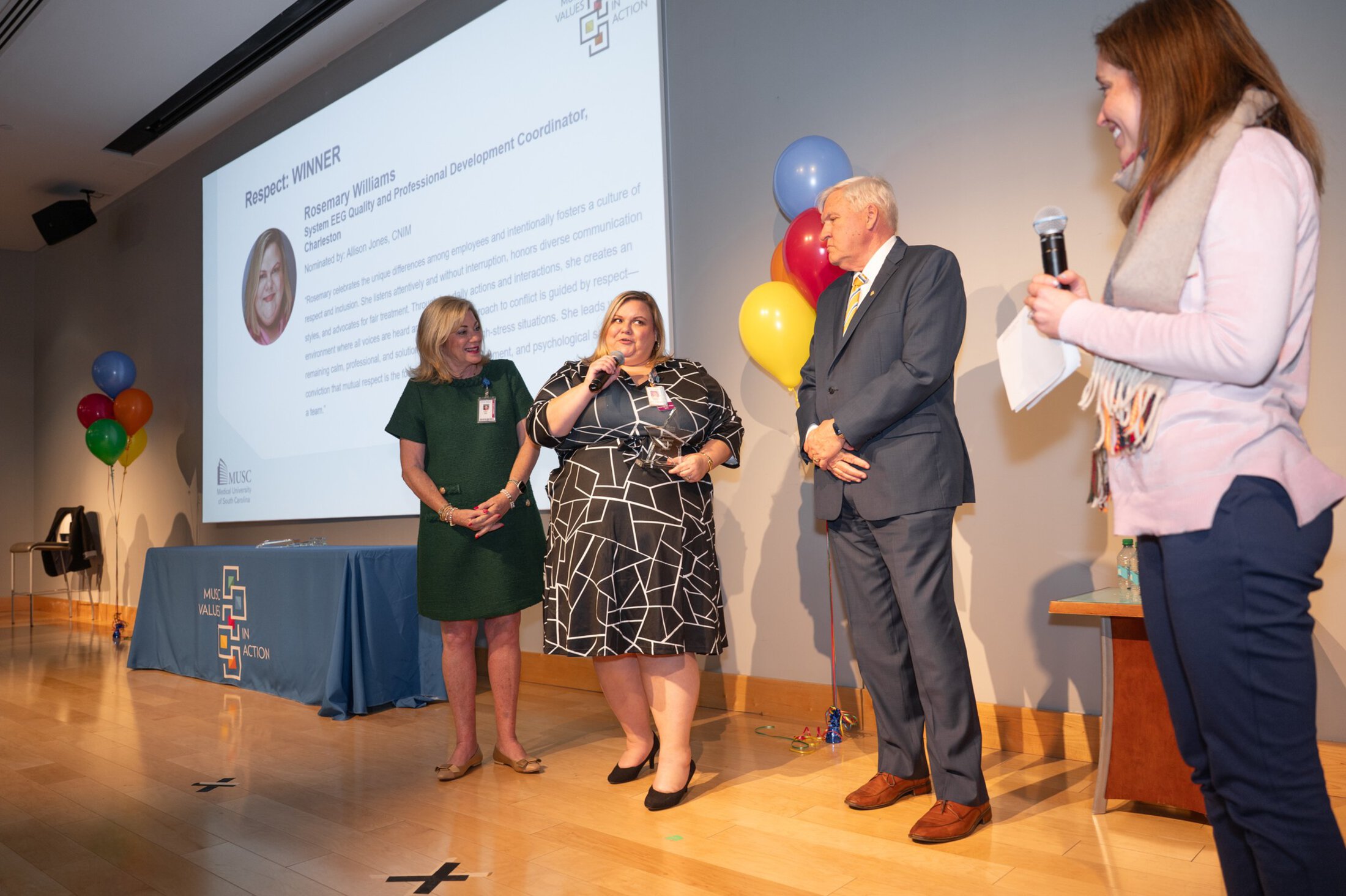 VIA Rosemary williams with Coles and Allison Jones, Dr Cole and Mrs Cole standing on a stage speaking