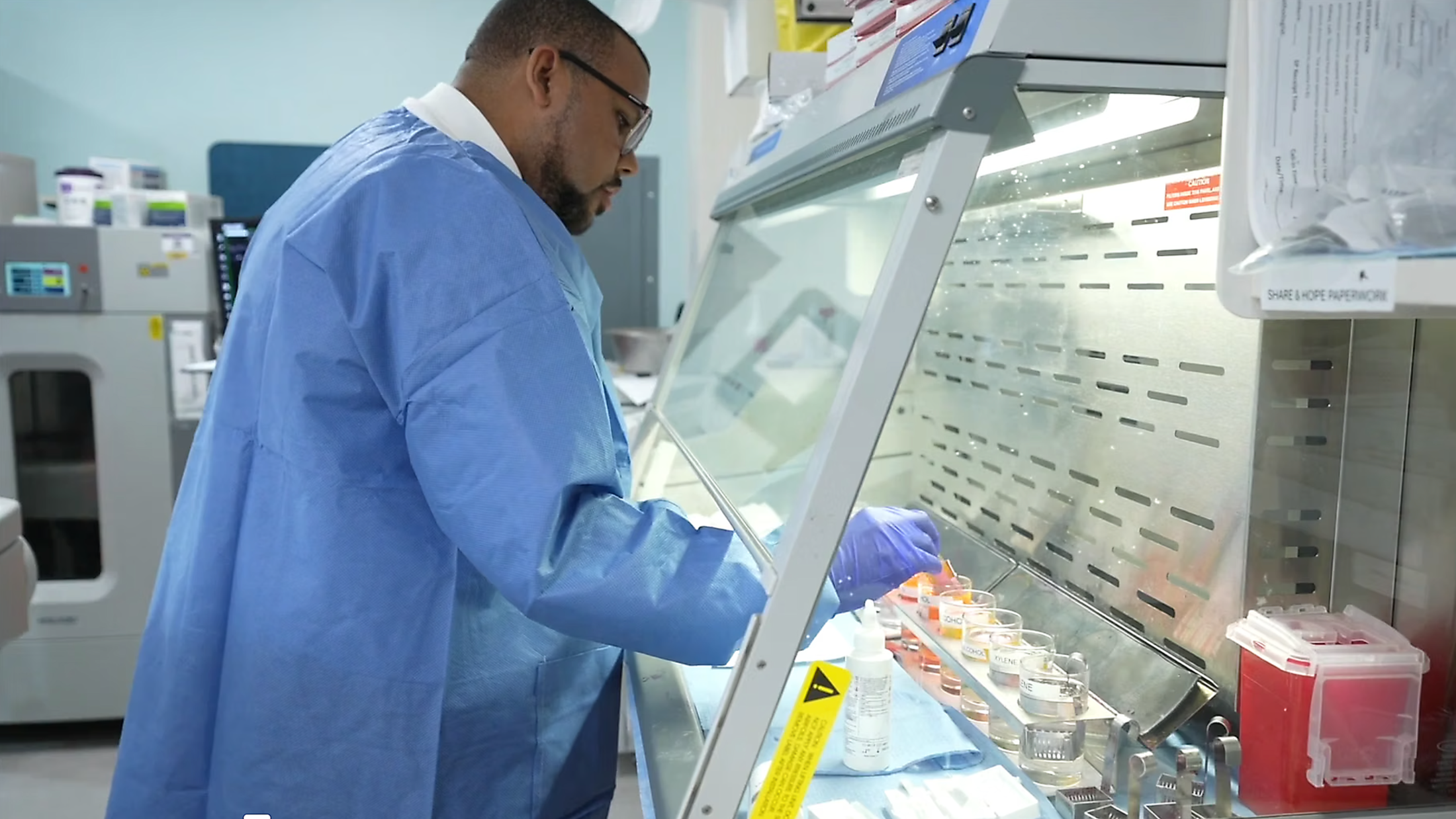 A man wearing blue scrubs tests tissue samples in the pathology lab.