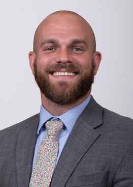 Tyler Vasas wearing a grey sport coat with blue shirt and tie