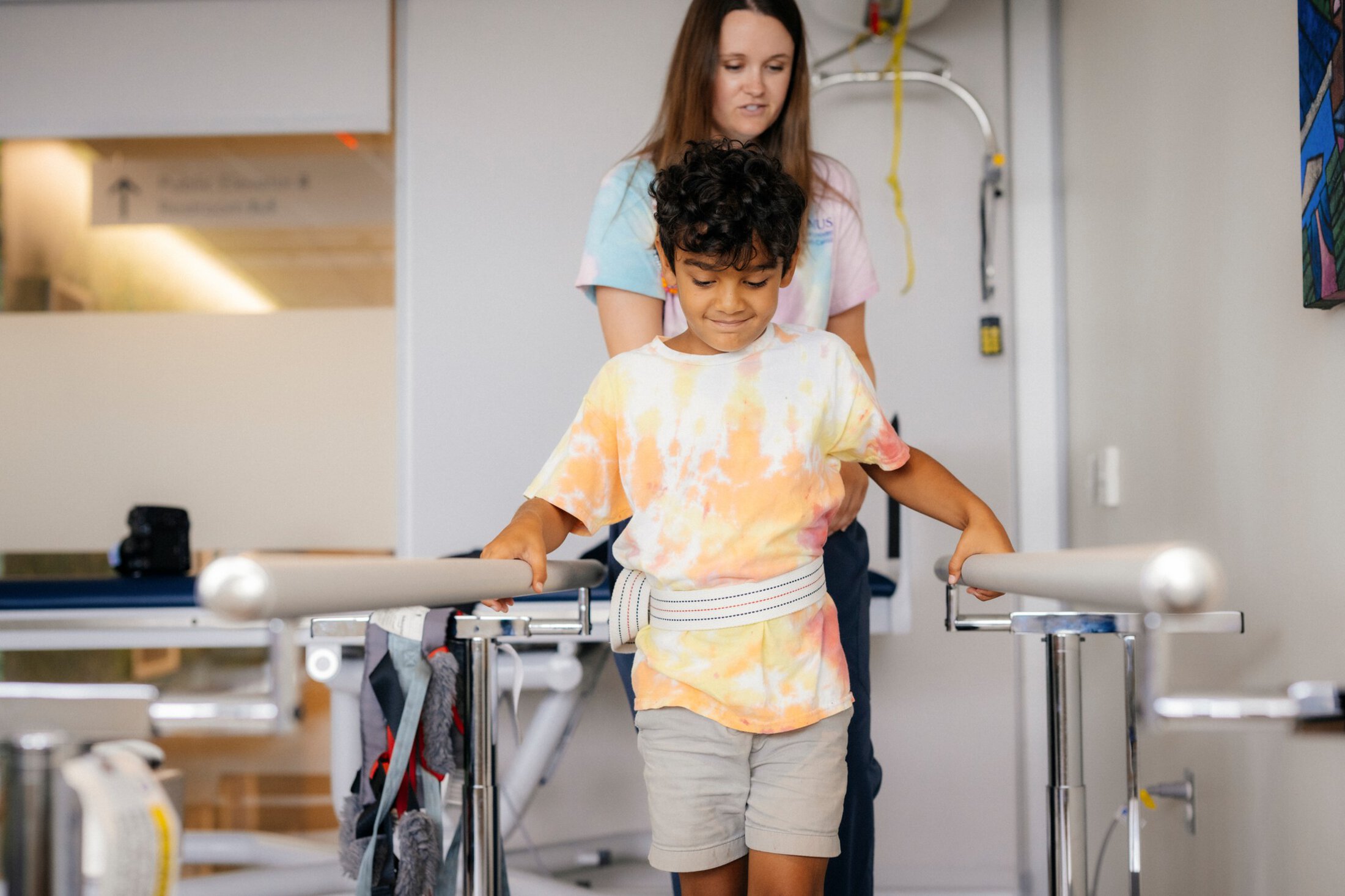 Child walking with strap attached to bar as part of occupational therapy with their doctor.