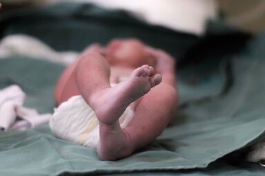 A newborn baby lying on a bed. The feet are in focus.