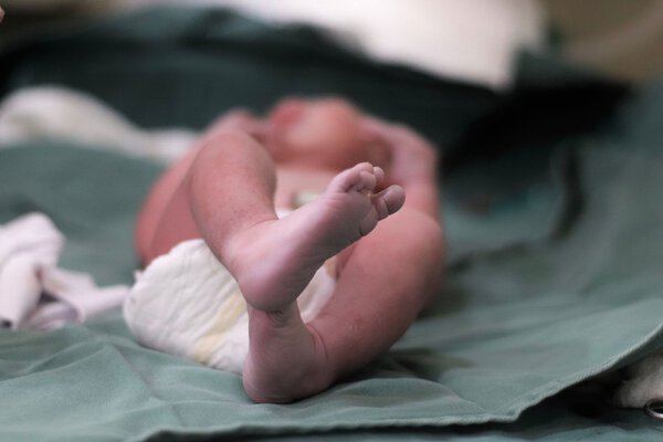 A newborn baby lying on a bed. The feet are in focus.