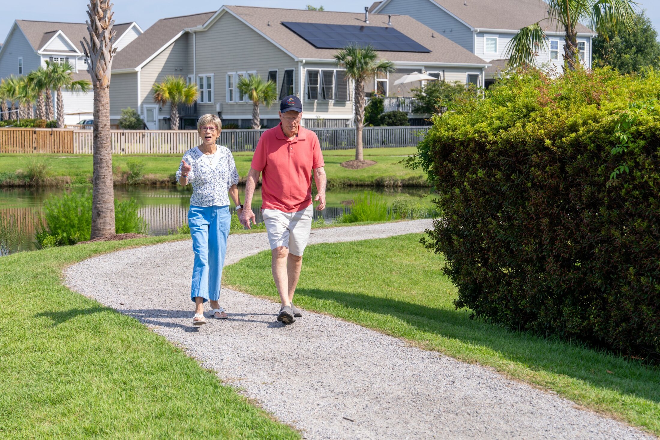 A couple walks along a gravel path, hand-in-hand, in a Lowcountry neighborhood.