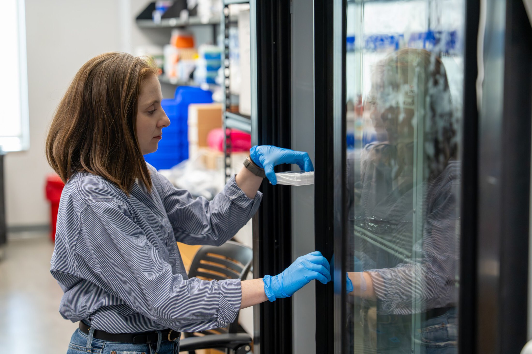 A researcher pulls a sample from a refrigerator in a lab.