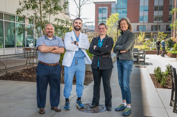A group of people stands in the MUSC courtyard with their arms crossed.