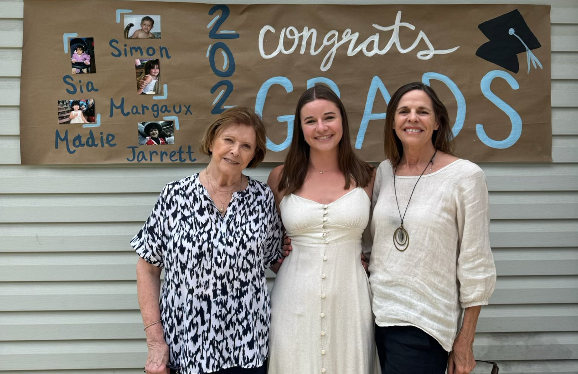three generations of women in front of a congratulatory graduation sign