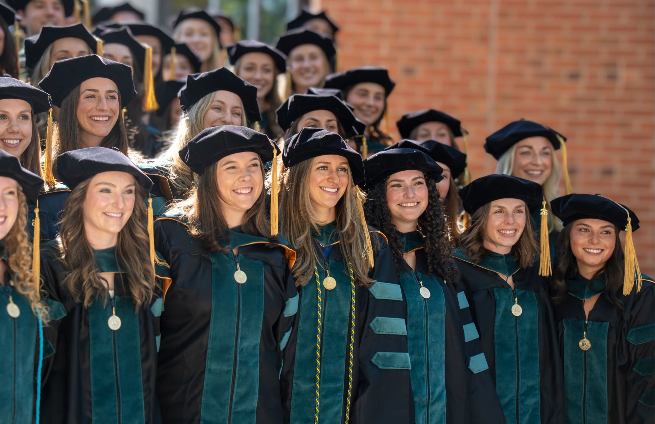 a group of women in caps and gowns pose for their graduation group photo