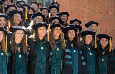 a group of women in caps and gowns pose for their graduation group photo