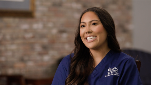 close up of a woman in navy scrubs smiling to the camera