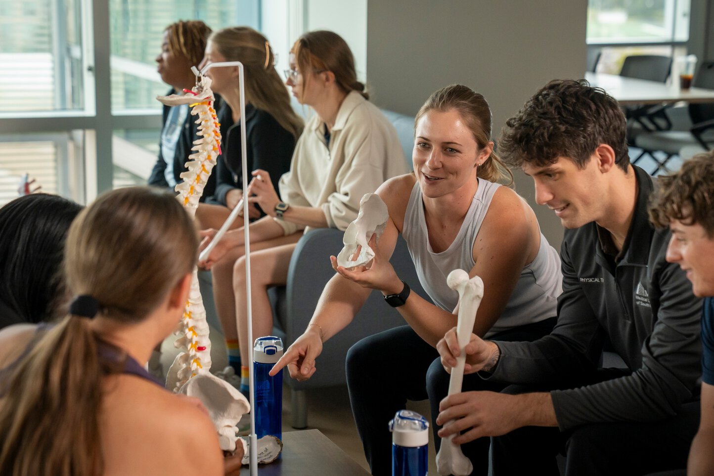 students seated and gathered around anatomical models