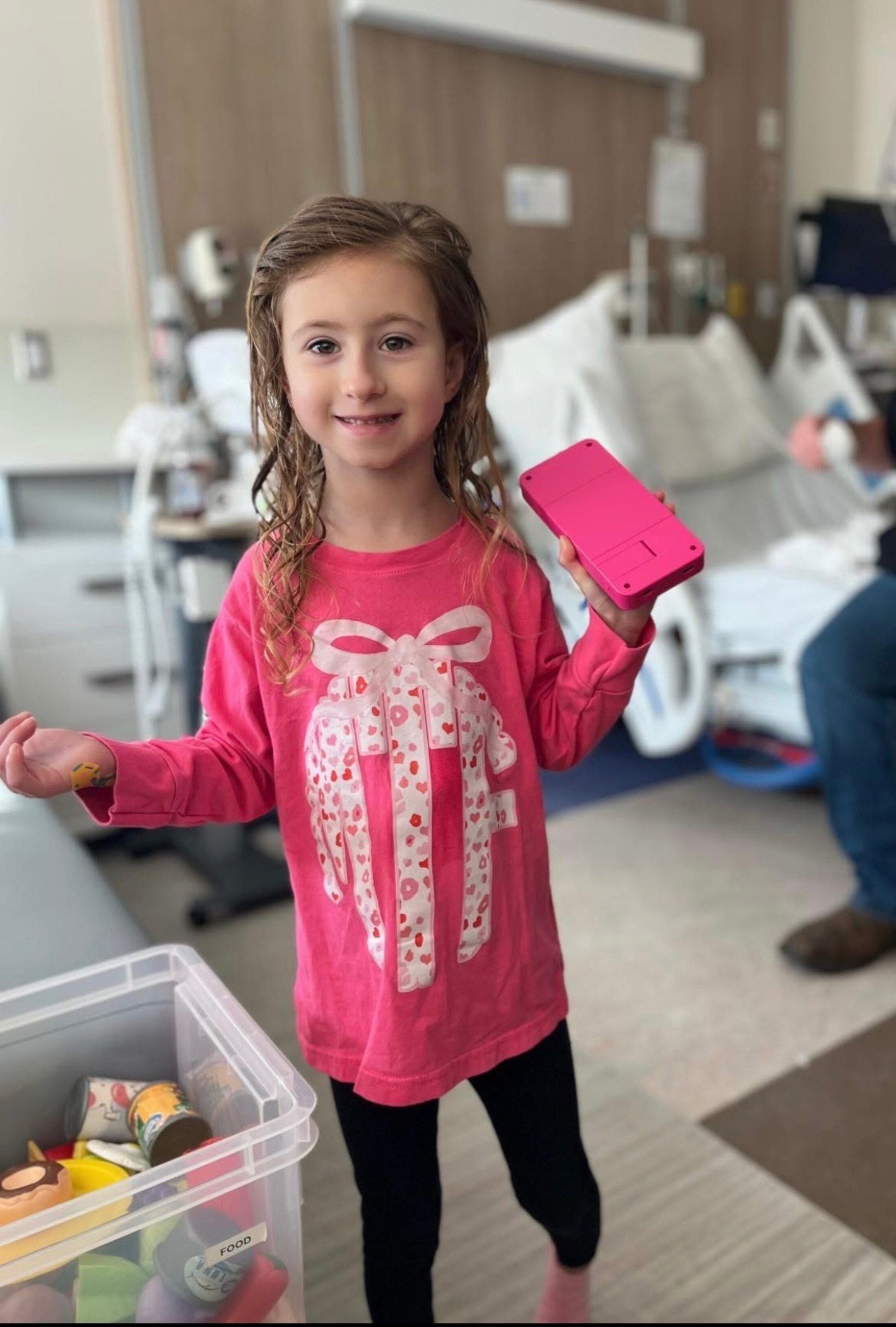Children patient wearing a pink shirt holding a fake pink phone