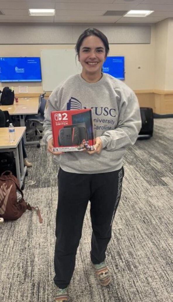 Student smiles while holding a boxed Nintendo Switch won at a Level Up financial literacy event.