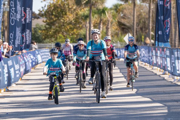 a woman and small boy ride down the Lowvelo finish line chute with another group of riders behind them