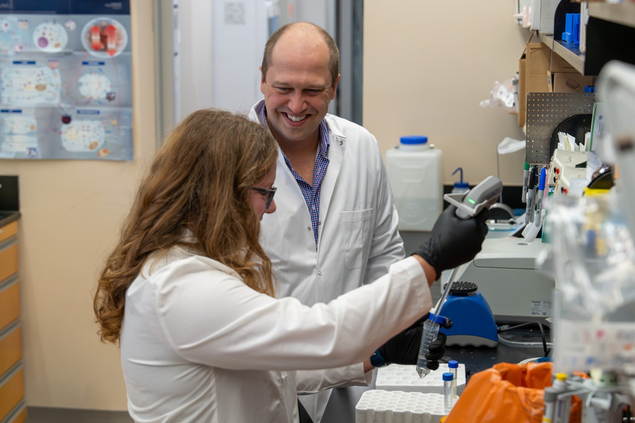 Aaron Hobbs with Hollings Cancer Center speaking with a colleague in a lab