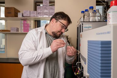 A scientist in a white lab coat tests a machine in the lab.