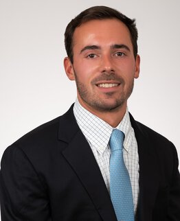 Joshua Lucas wearing a dark sport coat with dress shirt and blue tie