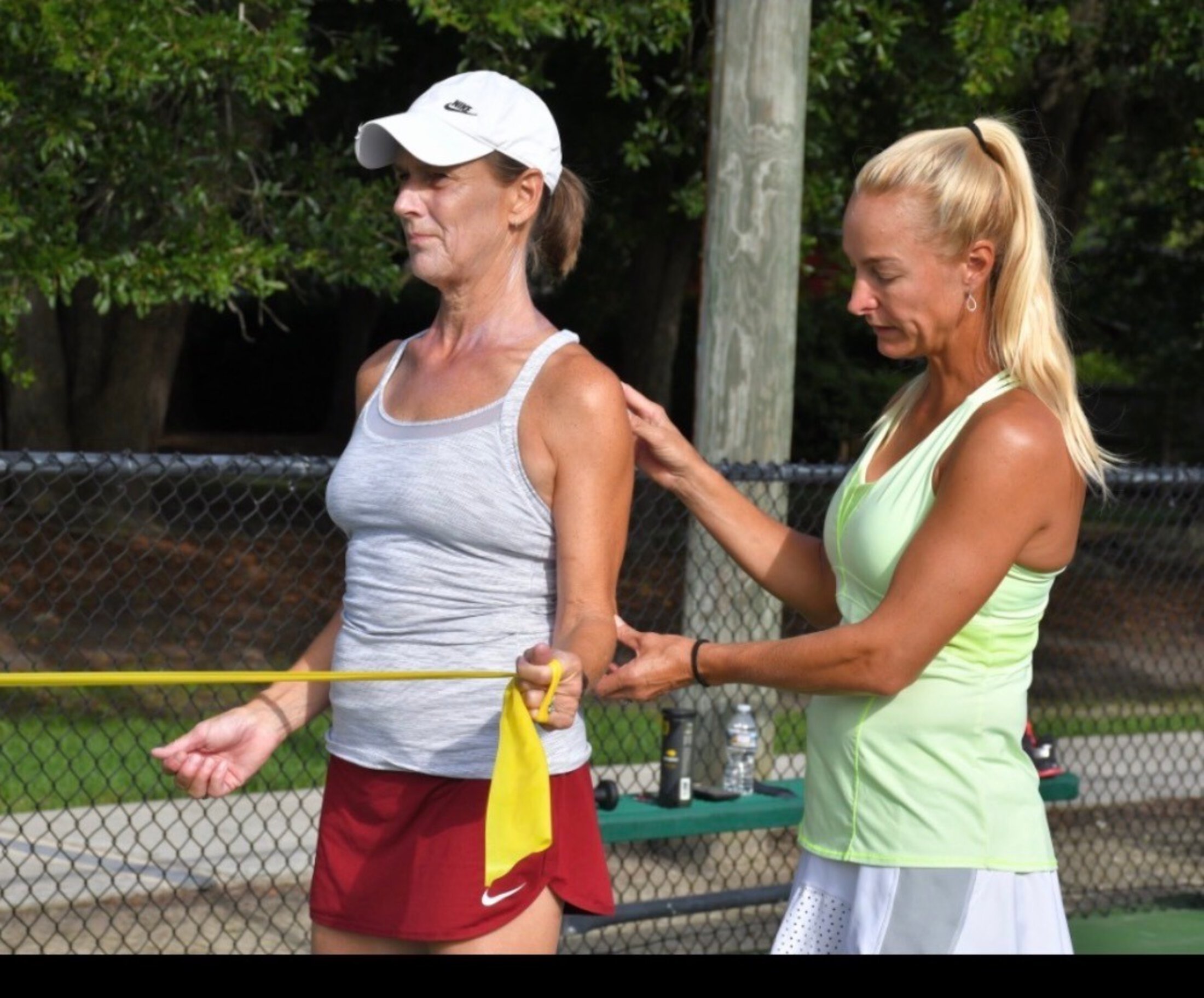 A physical therapist helps a woman walk outside.