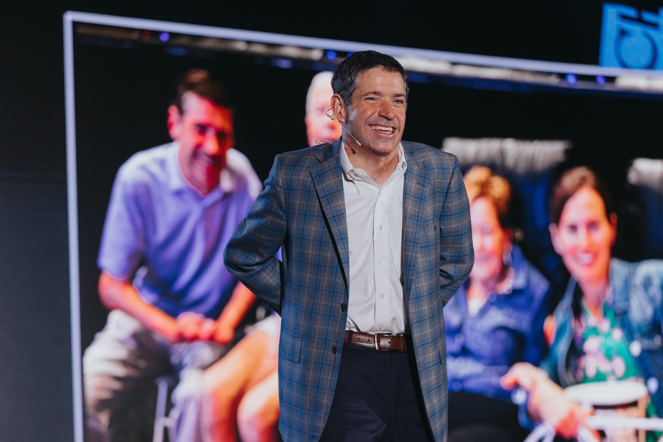A speaker stands on stage with a microphone.