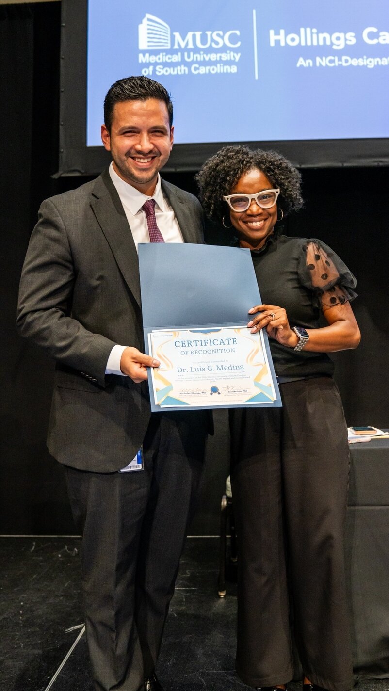 A smiling man and woman hold a certificate of recognition between them.