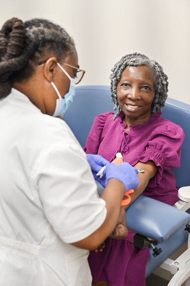 A woman sits in a phlebotomist's chair and gets her blood drawn.