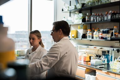 Norris Gensemer wearing lab coats inside lab discussing results