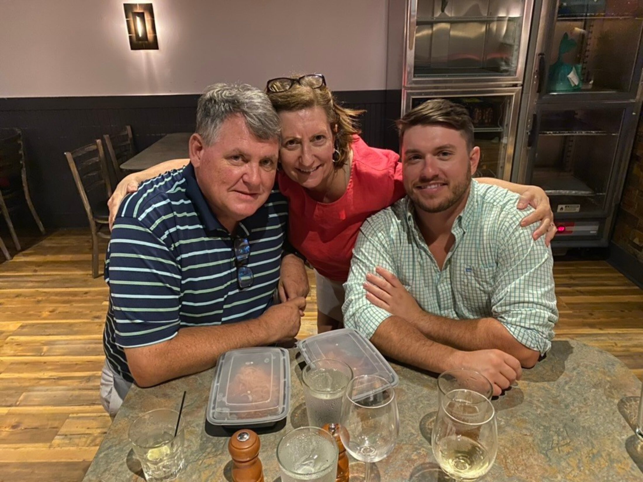 2 men and 1 woman pose together at a restaurant.