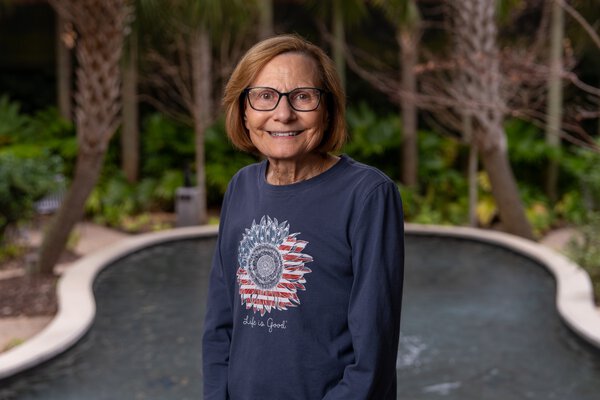 A woman poses in a garden setting.