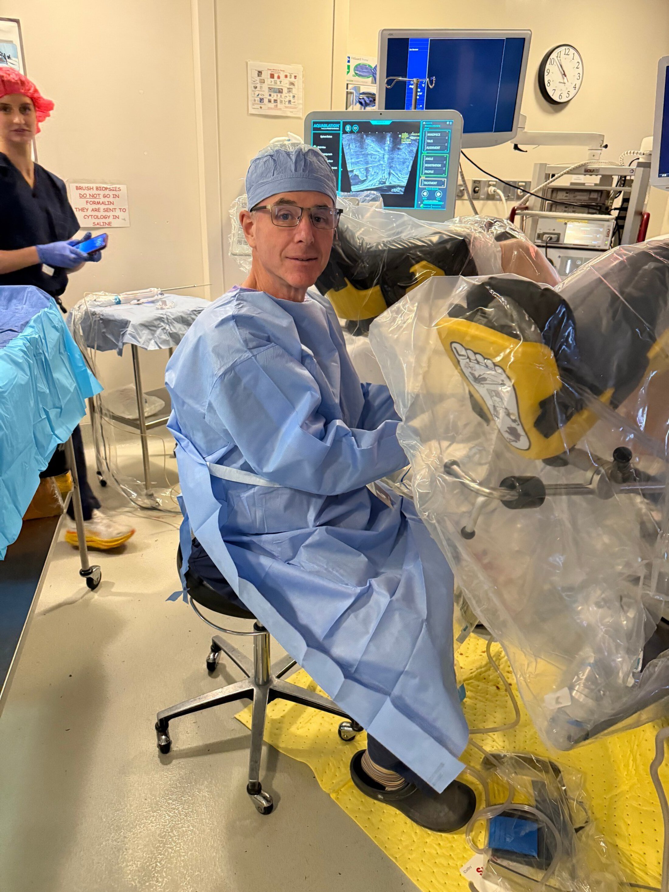 A doctor in scrubs prepares for aquablation procedure in a surgical suite.