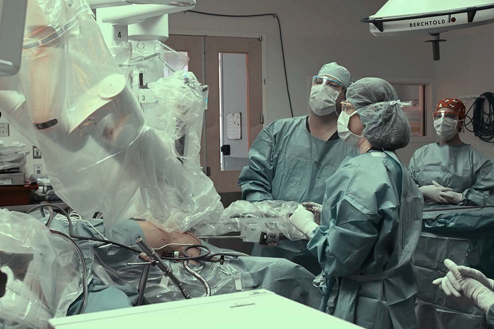 Dr. Aaron Lesher, center, performing robotic surgery.