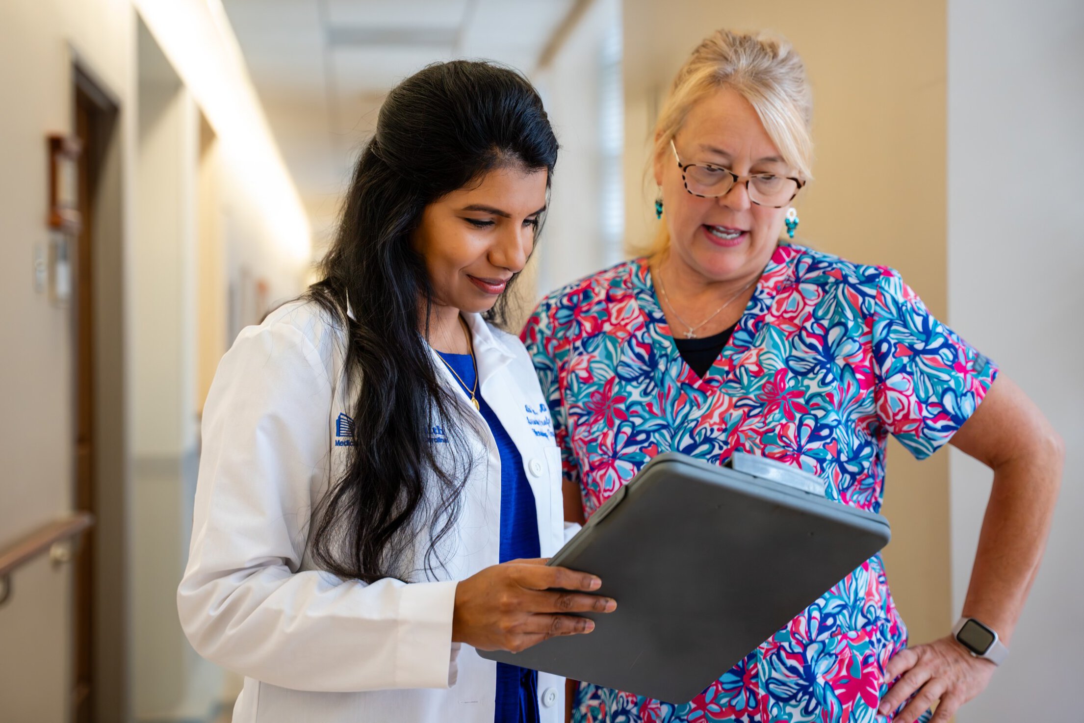 A doctor and nurse consult in a hall.